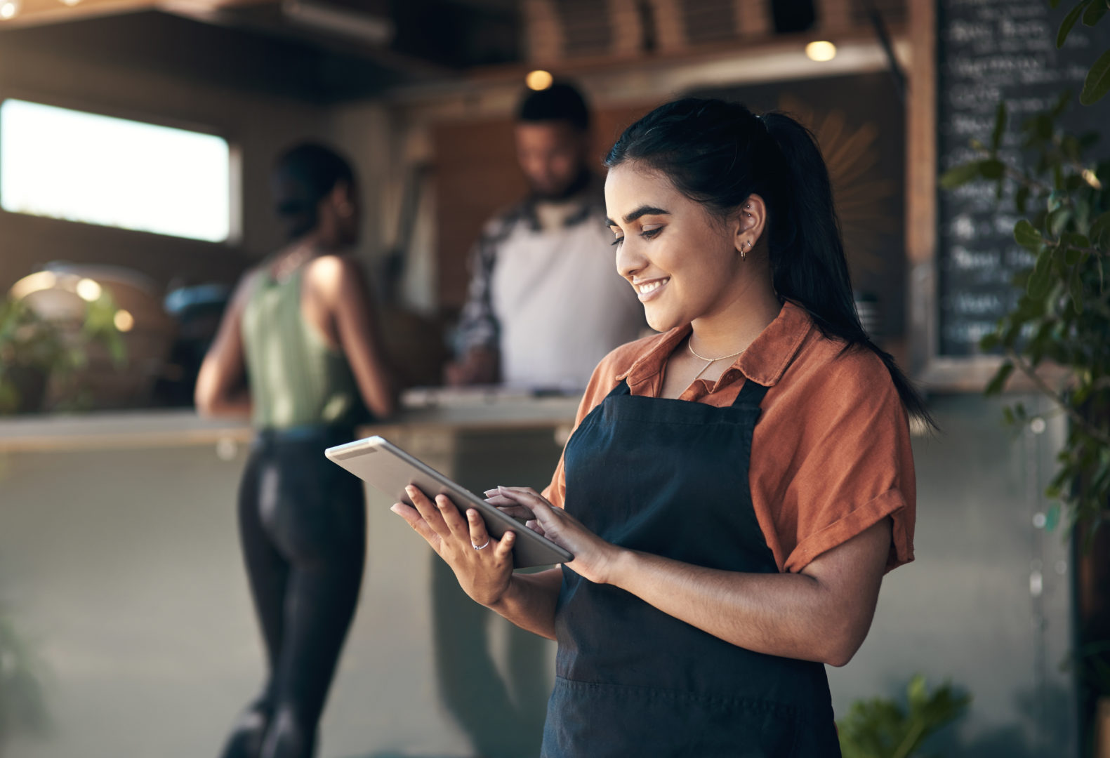 Shot of an attractive young woman standing outside her restaurant and using a digital tablet