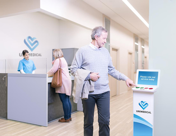 Man pressing smiley terminal button in healthcare clinic