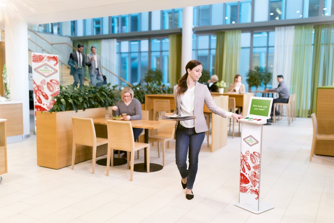 HappyOrNot in cafeteria woman pressing Smiley Terminal for feedback