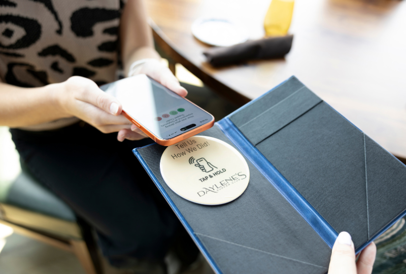 Guest tapping a HappyOrNot Smiley Sign in the billfold at Daylene’s Supper Club to share real-time dining feedback